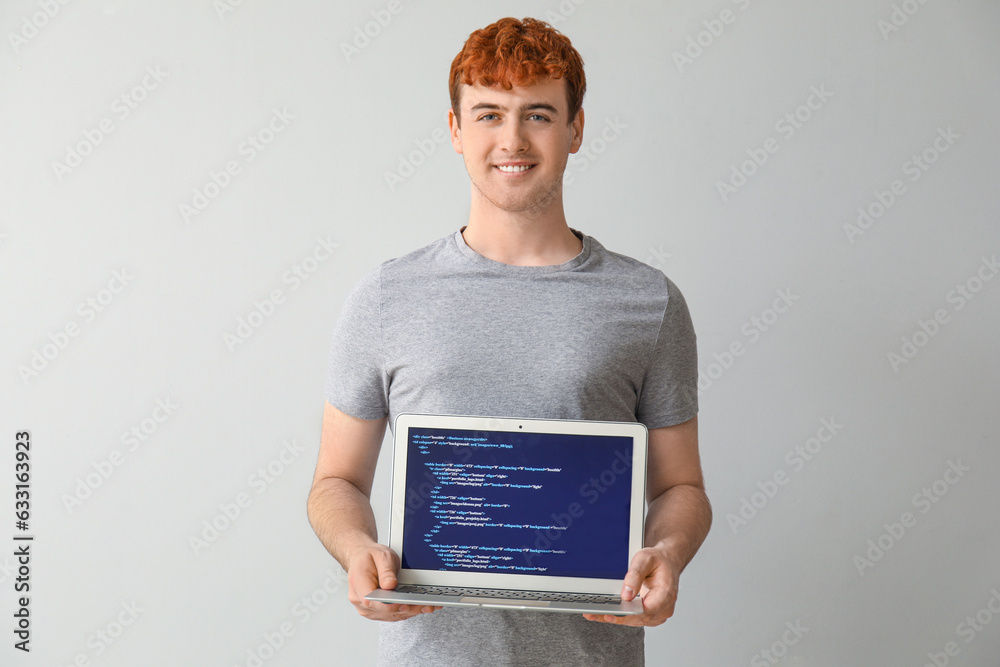 Male programmer with laptop on light background