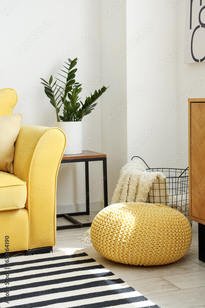 Pouf, basket with soft blanket and yellow sofa in interior of living room