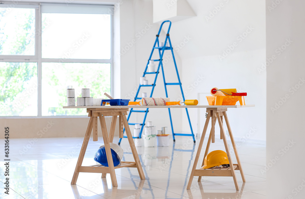 Table with paint cans and rollers in room