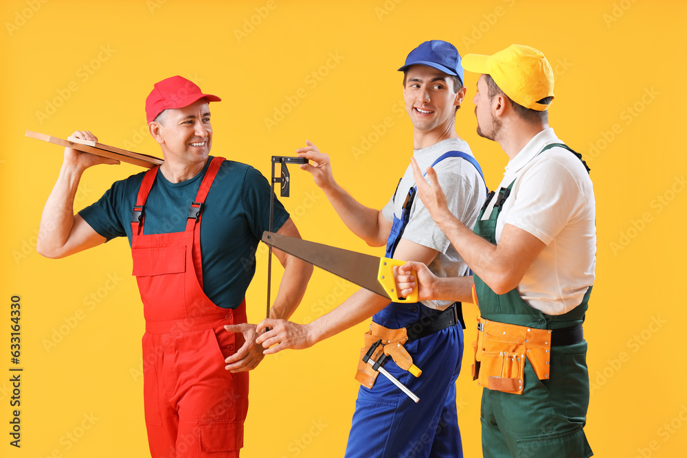 Team of male builders with tools on yellow background