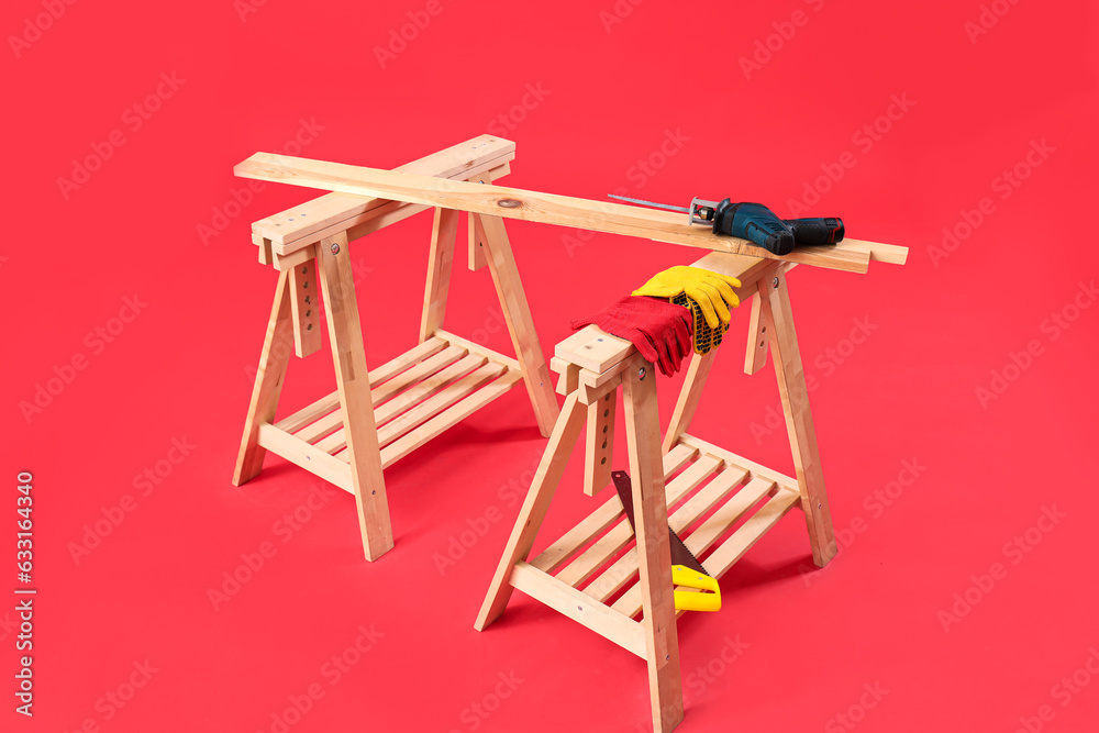 Wooden table with builders tools on red background