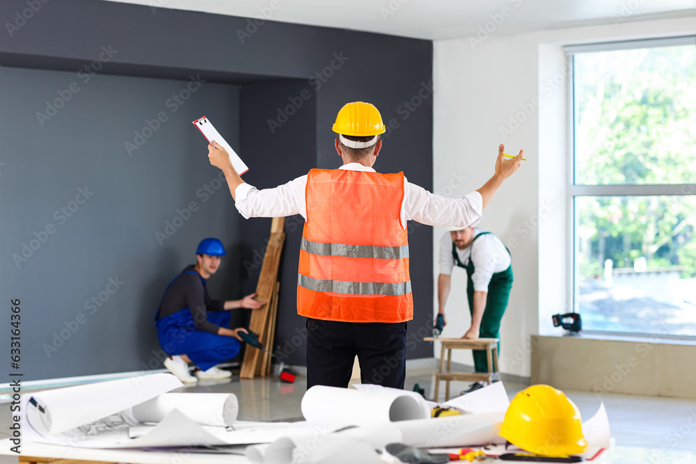 Team of male builders working in room, back view