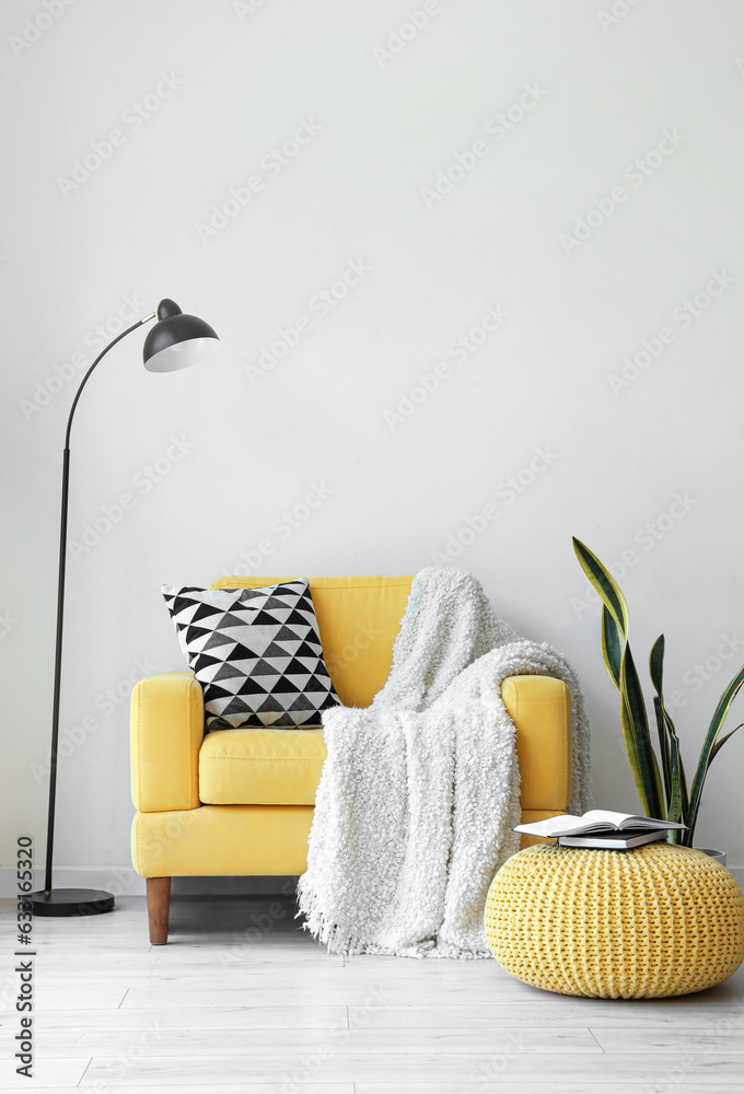 Yellow armchair with pillow and plaid in interior of living room