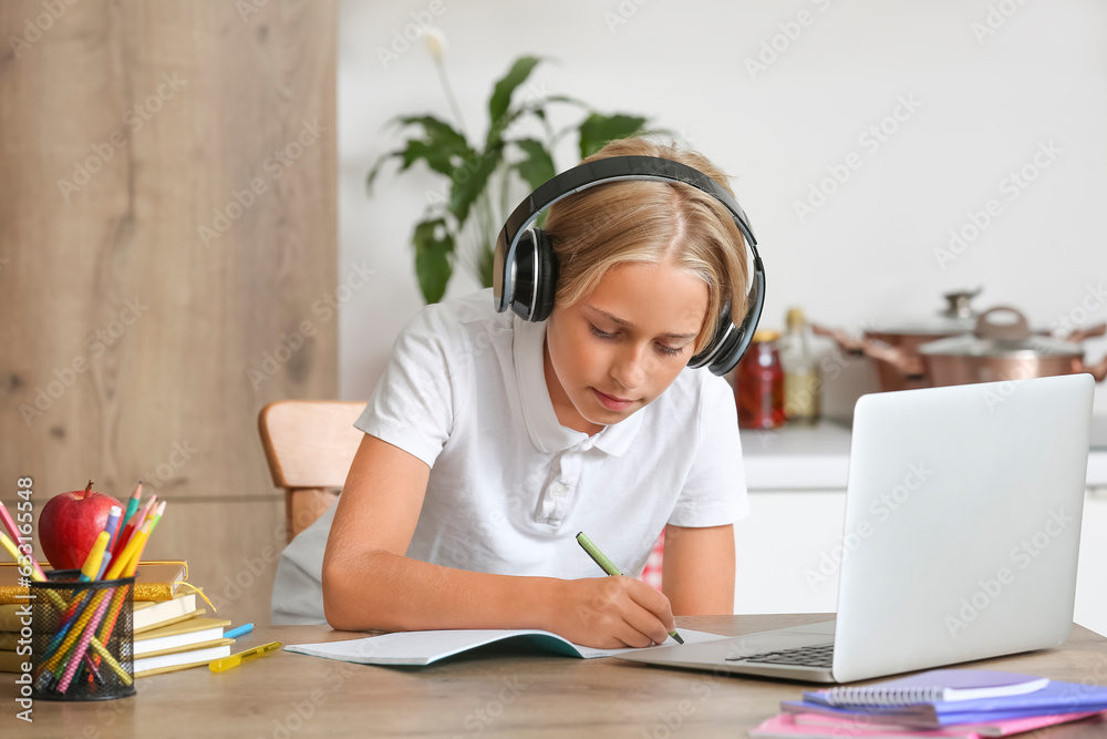 Little boy with headphones doing homework in kitchen