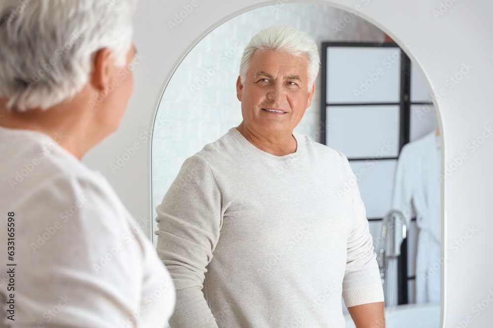 Senior man looking in mirror at home