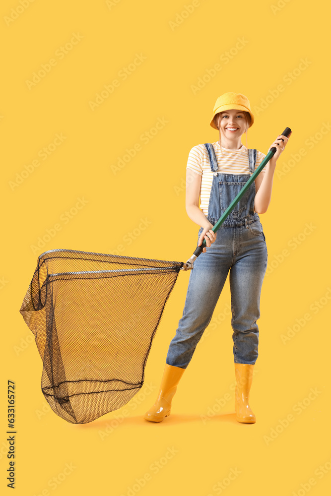 Happy young woman with landing net on yellow background