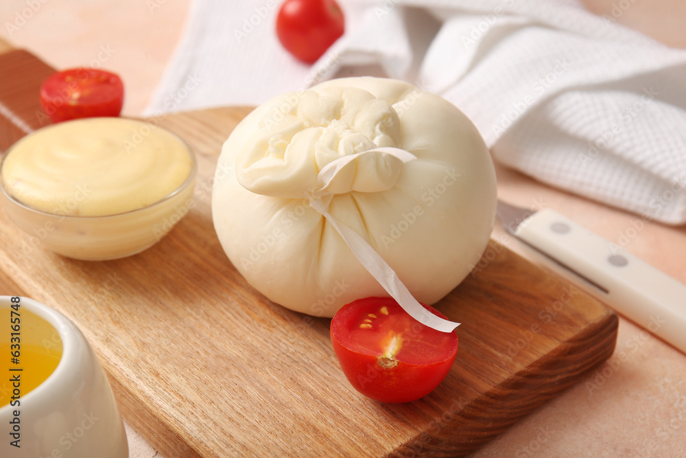 Wooden board with tasty Burrata cheese on beige background