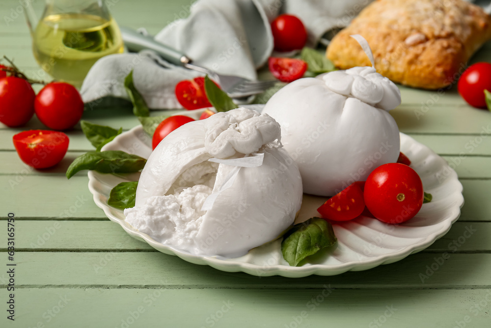 Plate with tasty Burrata cheese on green wooden background