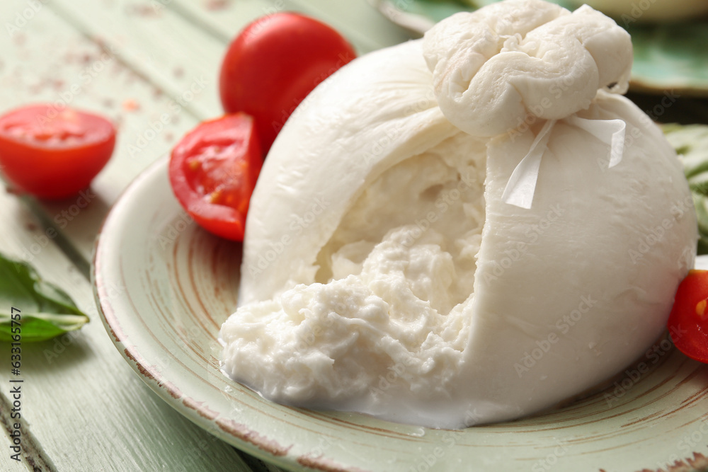 Plate with tasty Burrata cheese on green wooden background