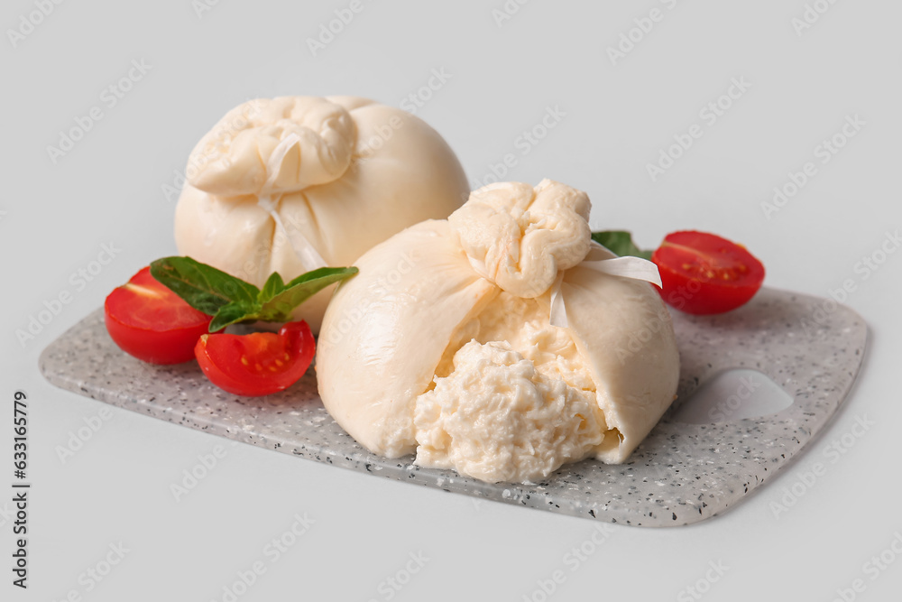 Board with tasty Burrata cheese on grey background