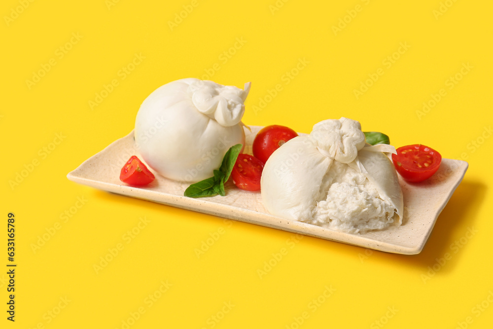 Plate with tasty Burrata cheese on yellow background