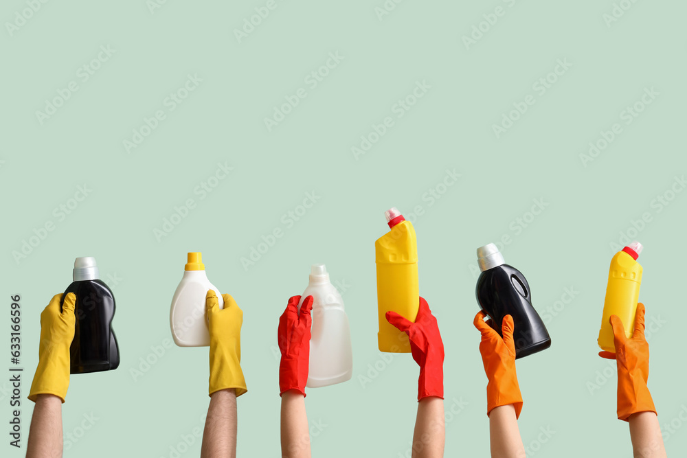 Women with bottles of detergent on green background