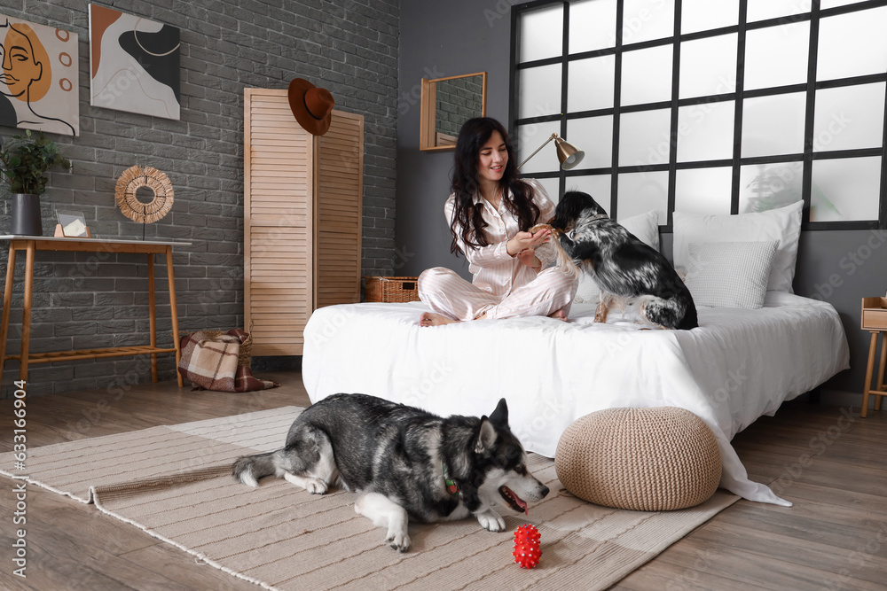 Young woman with cute dogs in bedroom