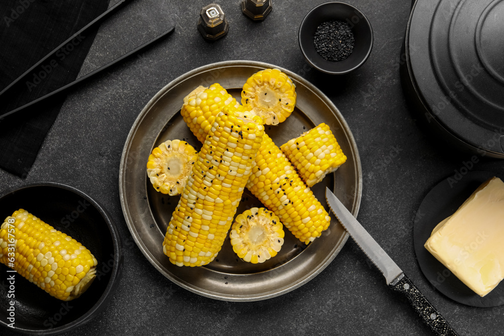 Plate and bowl with boiled corn cobs on black background