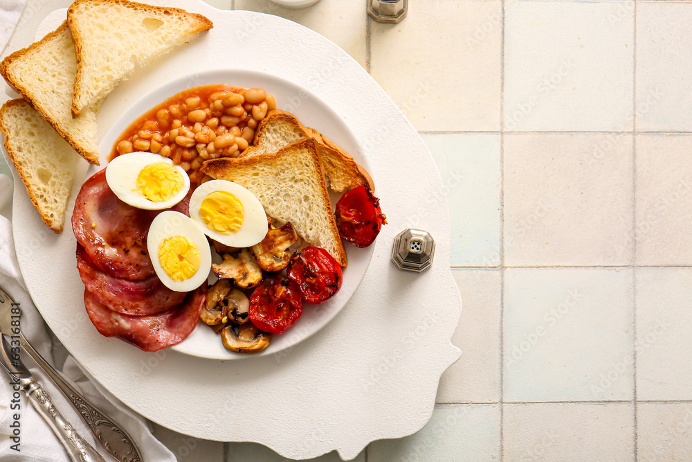 Plate of tasty English breakfast with boiled eggs on white tile background