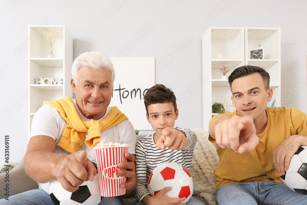 Little boy with his dad and grandfather watching football game at home