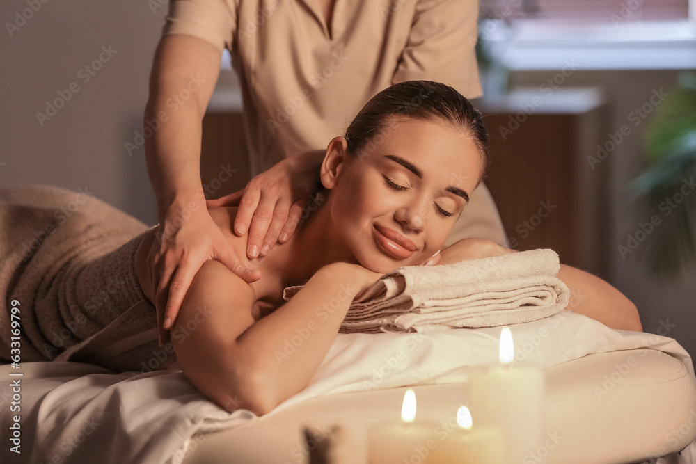 Pretty young woman having massage in spa salon