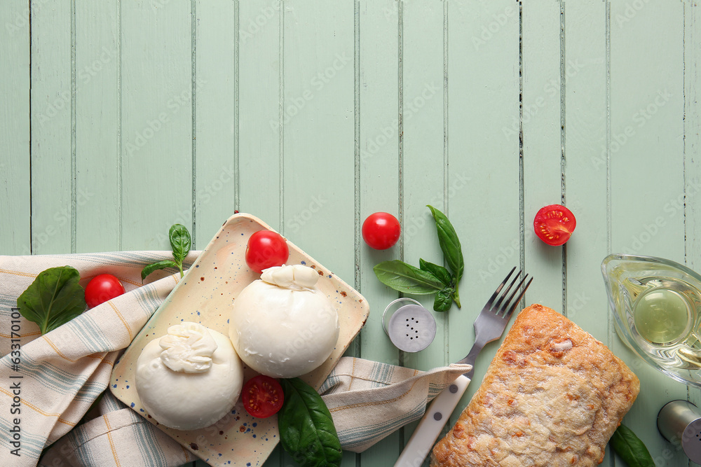 Plate of tasty Burrata cheese with basil and tomatoes on green wooden background