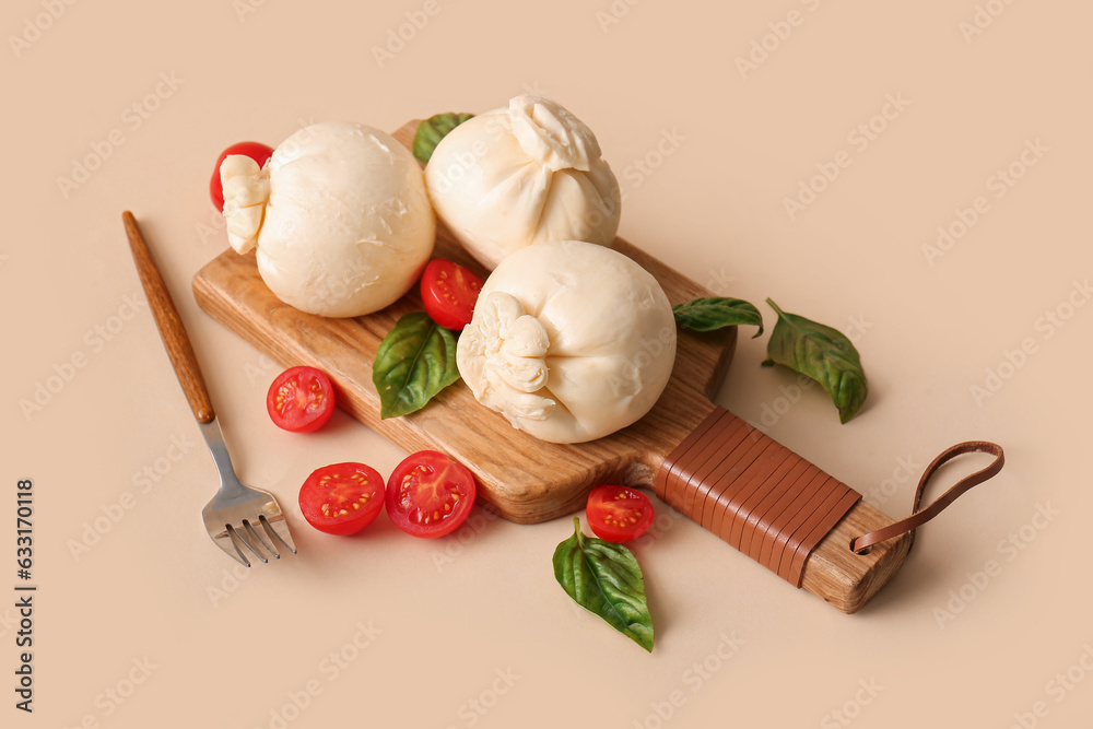 Wooden board of tasty Burrata cheese with basil and tomatoes on beige background