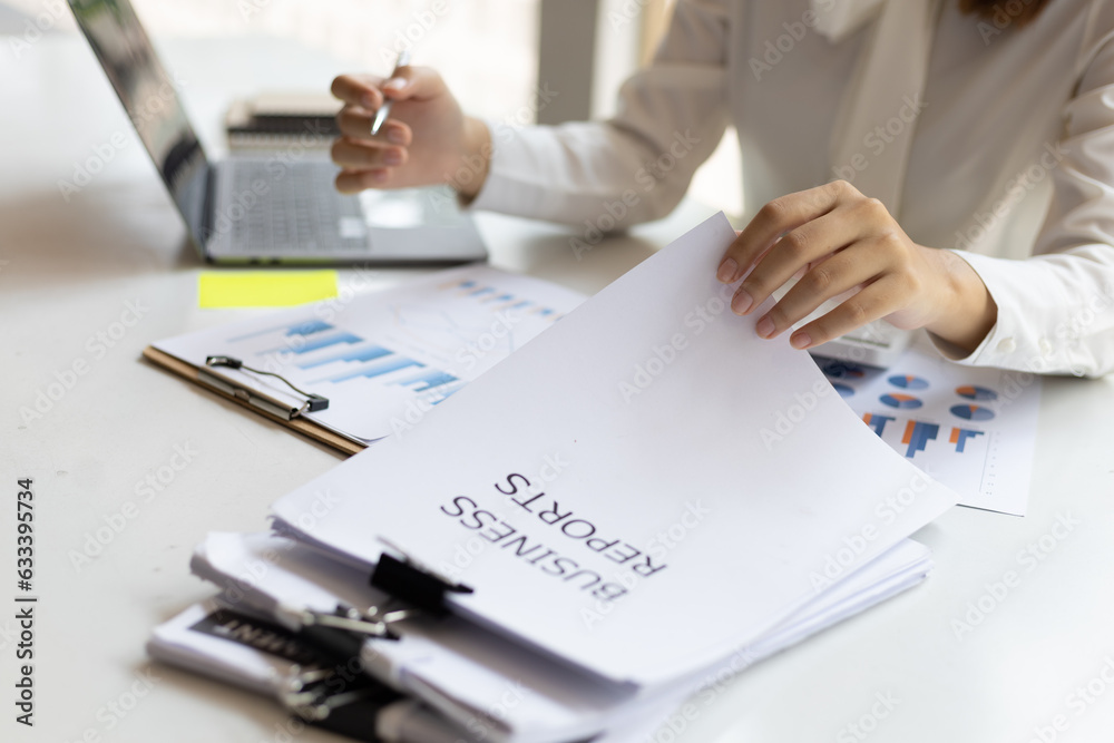 Business woman working on paperwork in the office, analysis of financial charts in business reports.