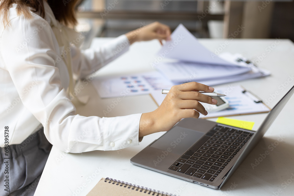 Businesswoman working on documents on laptop in office, business chart analysis in financial reports