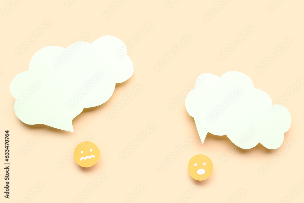 Paper faces with blank speech bubbles on beige background