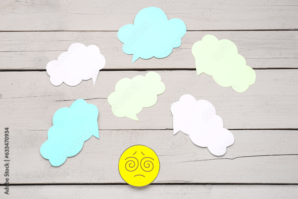 Confused paper face with blank speech bubbles on grey wooden background