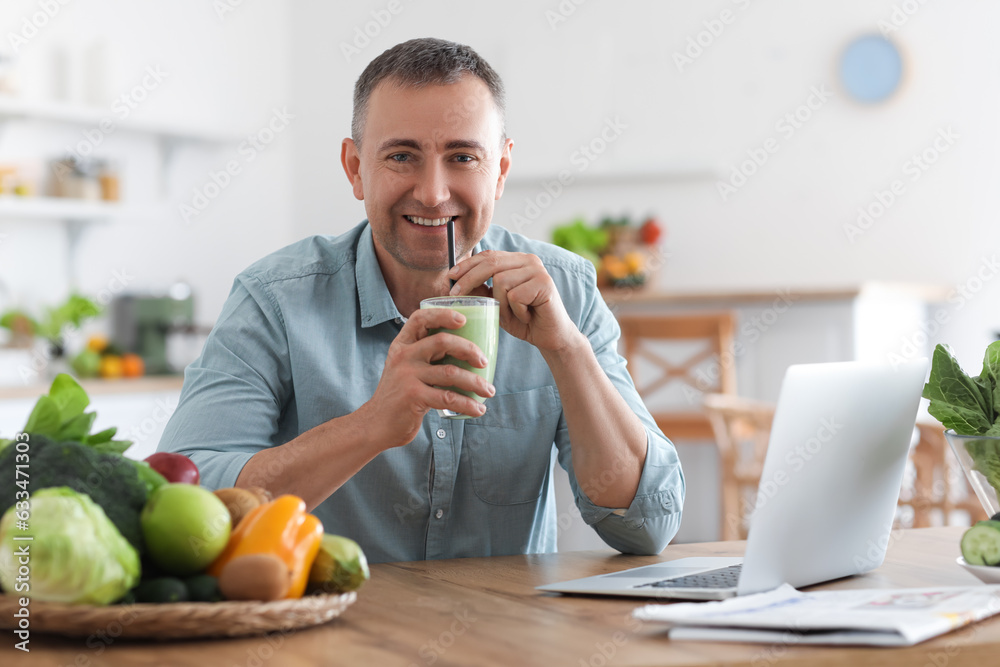 Mature man drinking fresh vegetable smoothie in kitchen