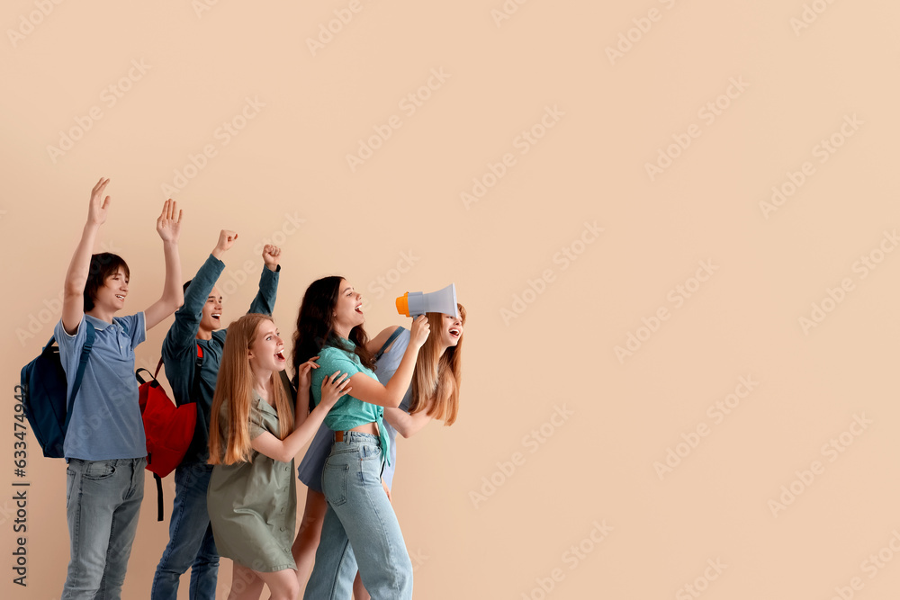 Group of students with megaphone shouting near beige wall