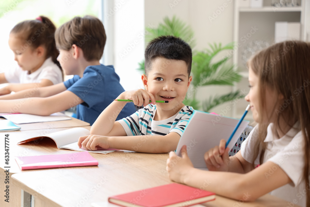 Little schoolboy having lesson in classroom