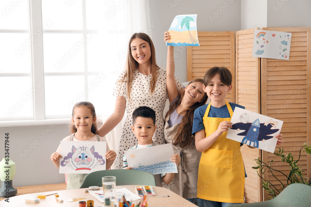 Little pupils with drawings and teacher in art class