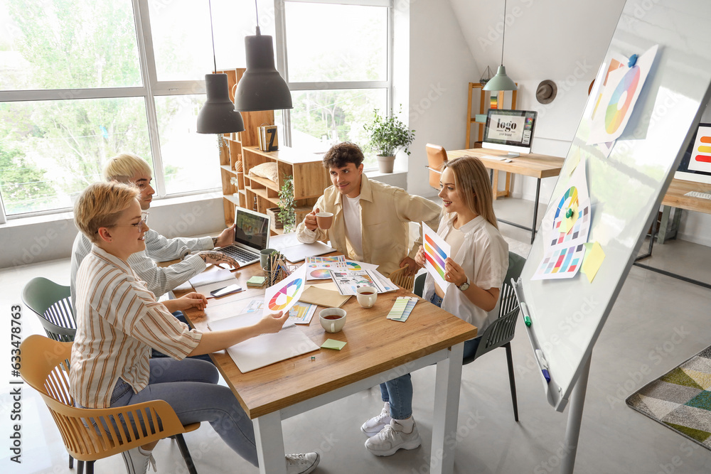 Team of graphic designers working with color palettes at table in office