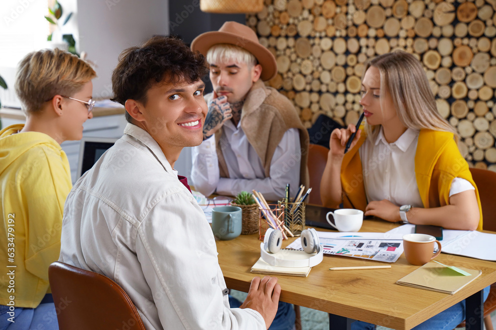 Male graphic designer working with co-workers at table in office