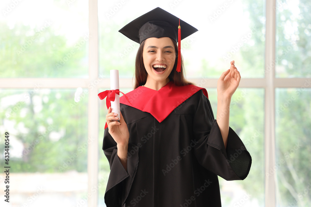 Happy female graduate student with diploma near window in room