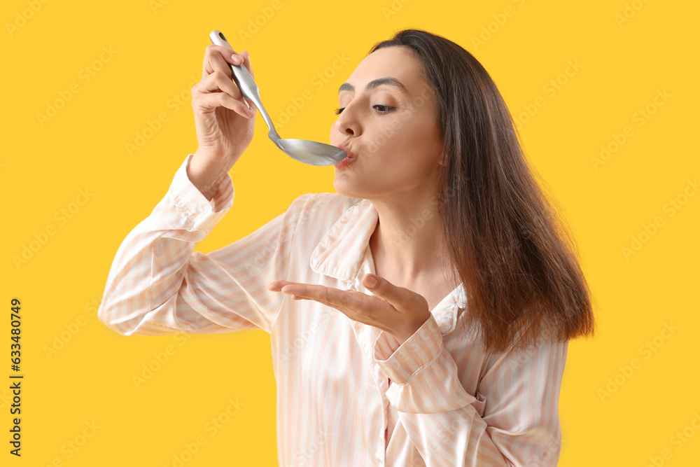 Young woman with ladle on yellow background