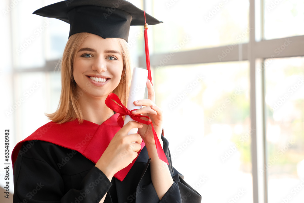 Female graduate student with diploma near window in room