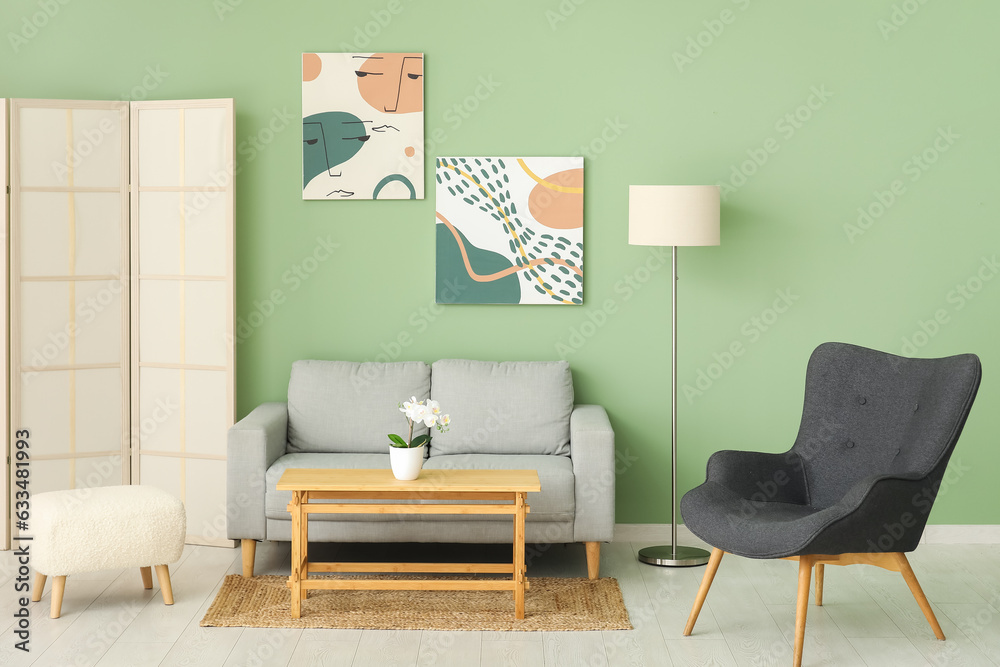 Interior of living room with cozy grey sofa, armchair and paintings