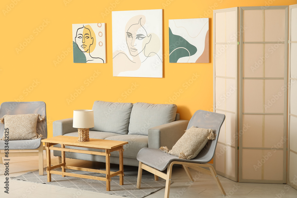 Interior of stylish living room with grey sofa, armchairs and paintings