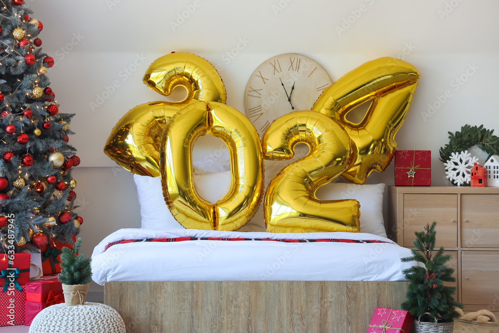 Balloons in shape of figure 2024 on comfortable bed in bedroom with Christmas decor