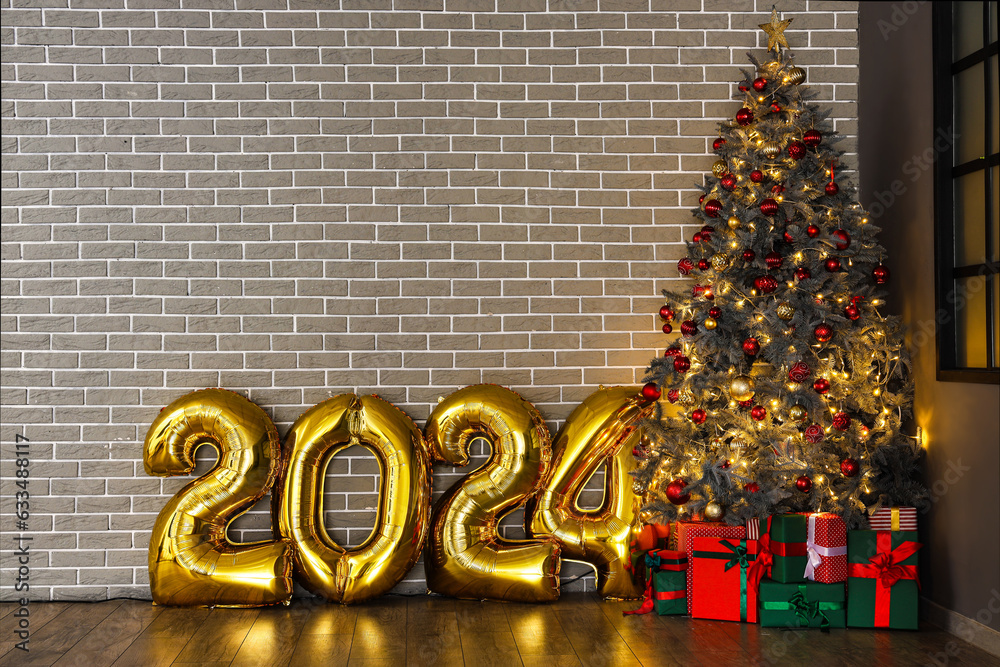 Balloons in shape of figure 2024 and Christmas tree with gifts near grey brick wall