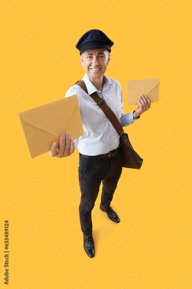 Mature postman with envelopes on yellow background