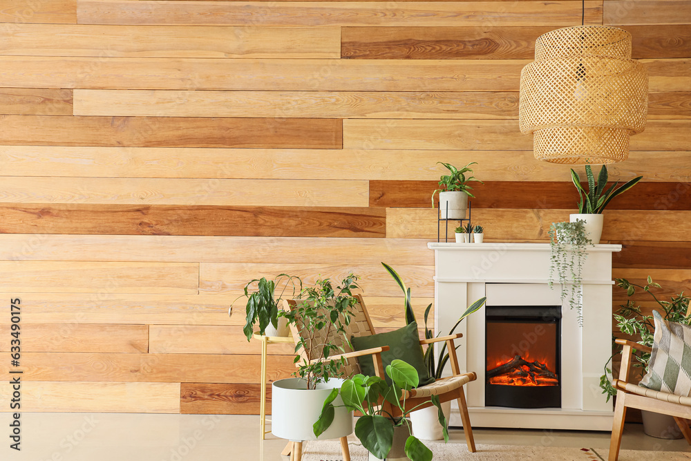 Stylish fireplace and armchairs near wooden wall