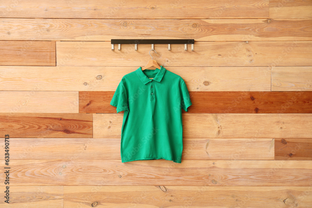 Stylish green t-shirt hanging on wooden background