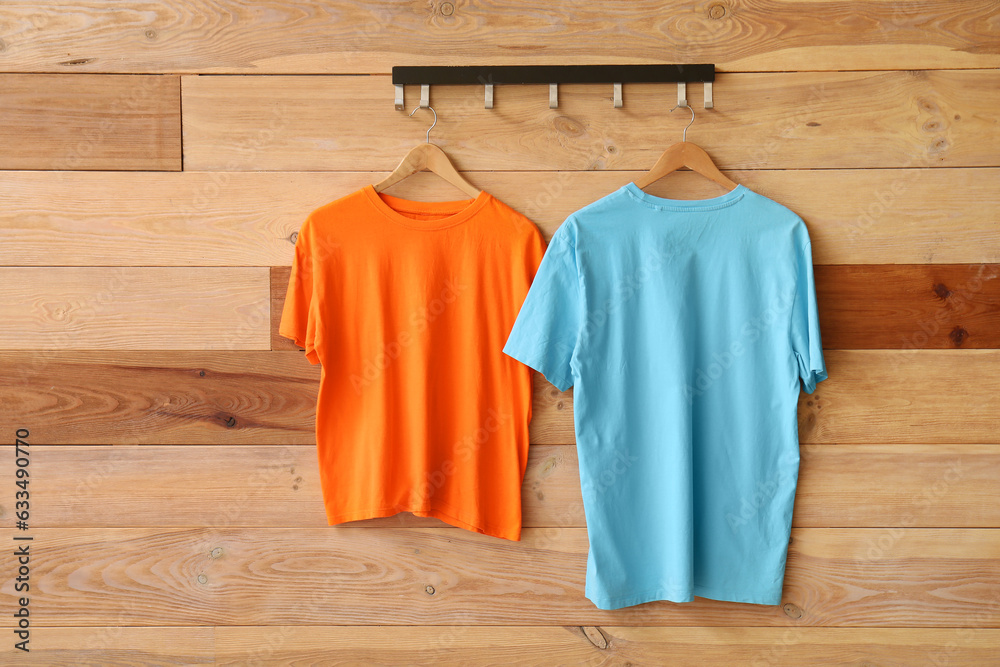 Stylish t-shirts hanging on wooden background