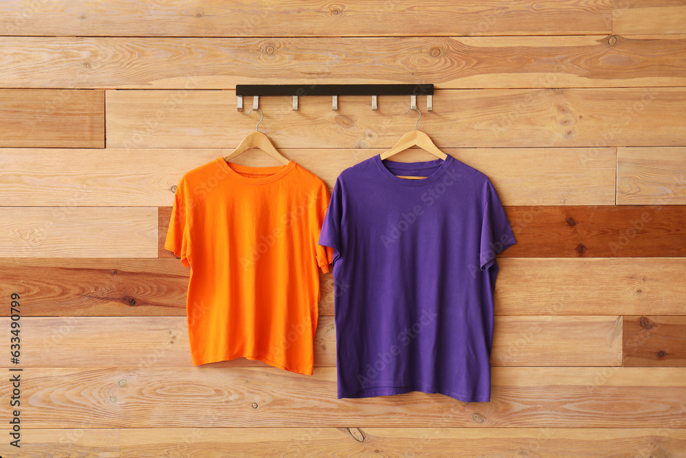 Stylish t-shirts hanging on wooden background