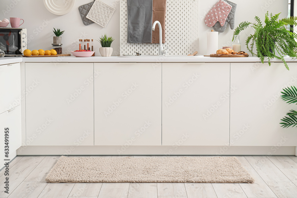 Interior of modern kitchen with stylish rug and white counters