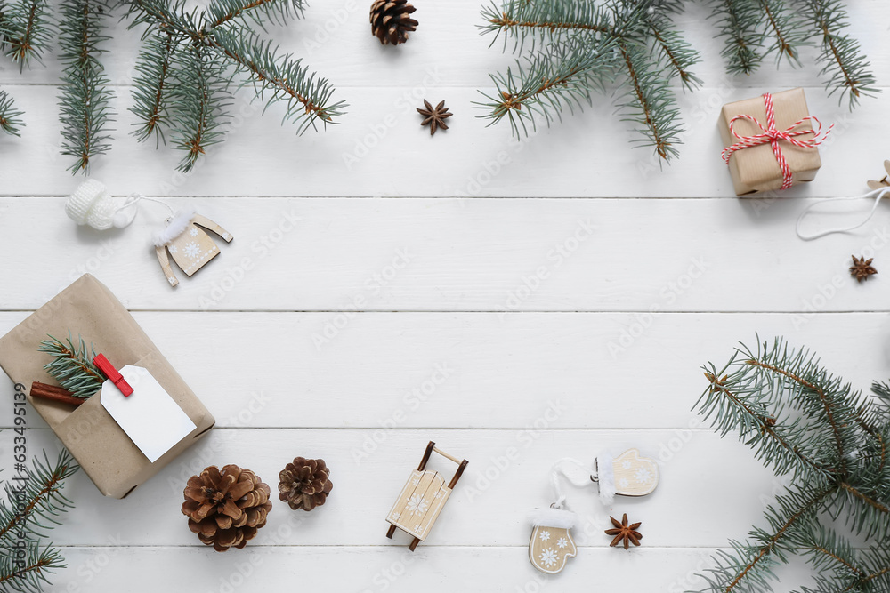 Frame made of Christmas tree branches with cones and gift boxes on white wooden background