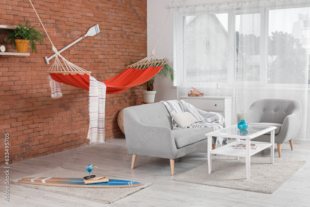 Interior of stylish living room with grey sofa, hammock and peddle