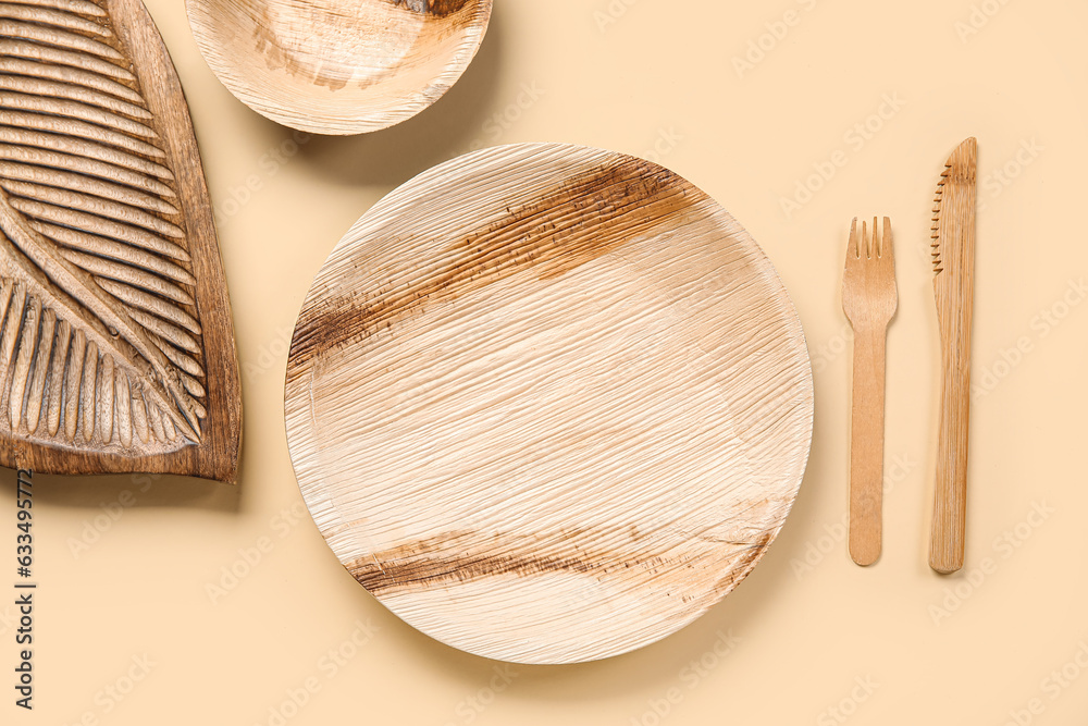 Different wooden tableware on beige background