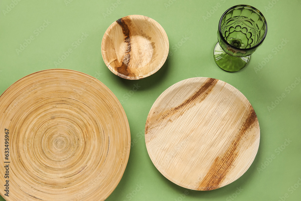 Wooden plates and glass on green background